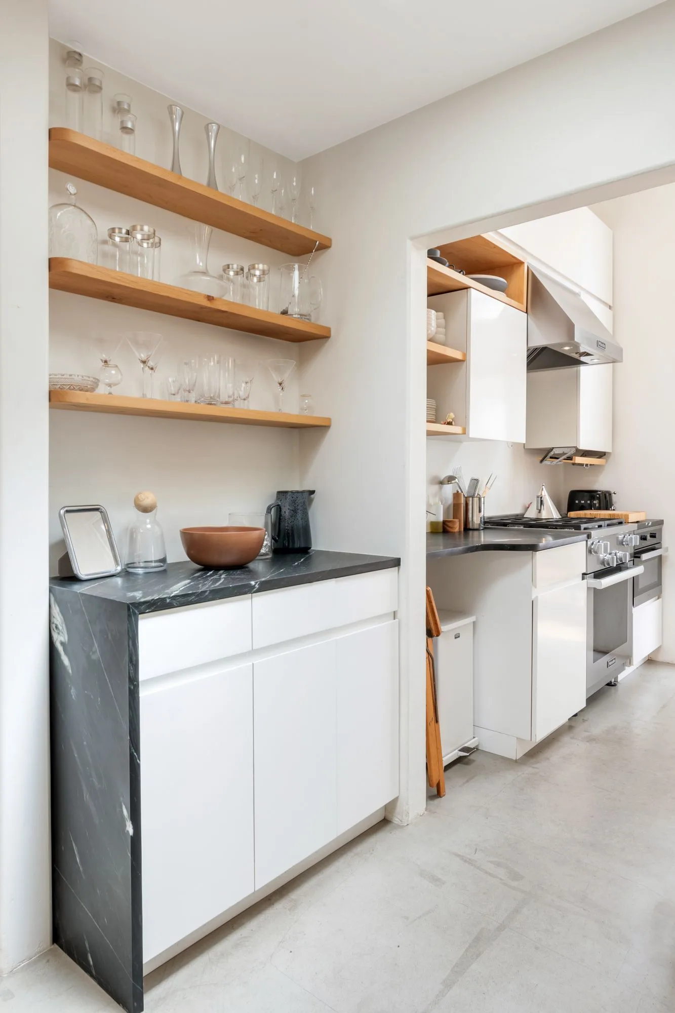 Kitchen with open timber shelves of glassware, white cabinets and a black stone counter — furniture and millwork designed and built by Jack Rusk (Oakland and Los Angeles, 2013–2018)