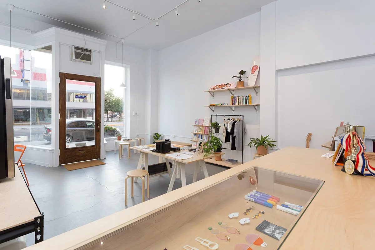 White shop interior with a pale timber counter, glass display case, shelves and worktables — furniture and millwork designed and built by Jack Rusk (Oakland and Los Angeles, 2013–2018)