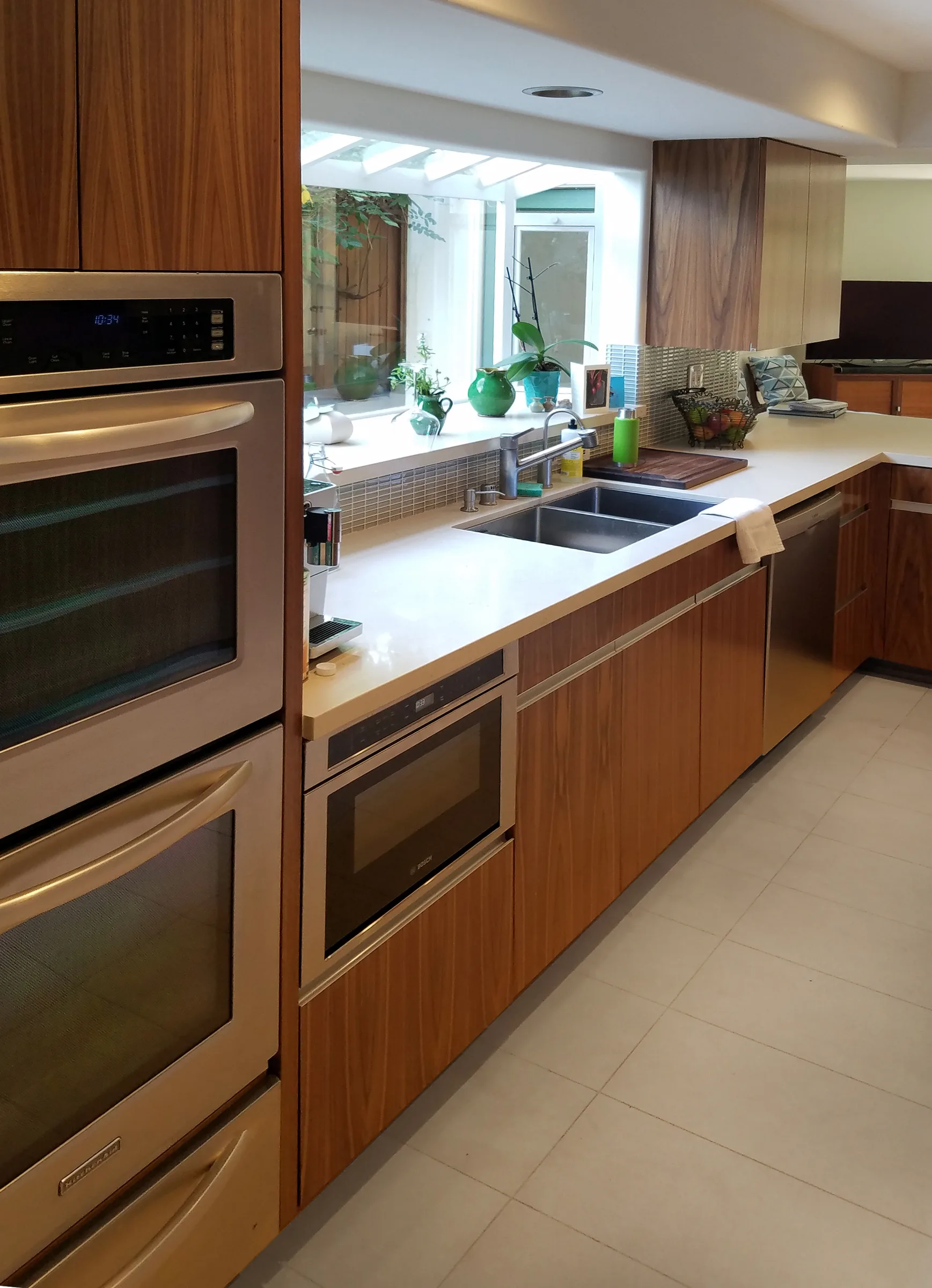 Walnut kitchen cabinetry with built-in wall ovens and a long counter beneath a window — furniture and millwork designed and built by Jack Rusk (Oakland and Los Angeles, 2013–2018)