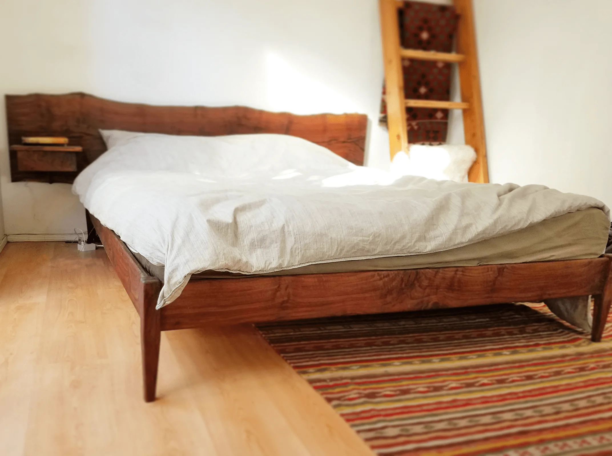 Walnut bed with a live-edge headboard and tapered legs on a striped rug — furniture and millwork designed and built by Jack Rusk (Oakland and Los Angeles, 2013–2018)