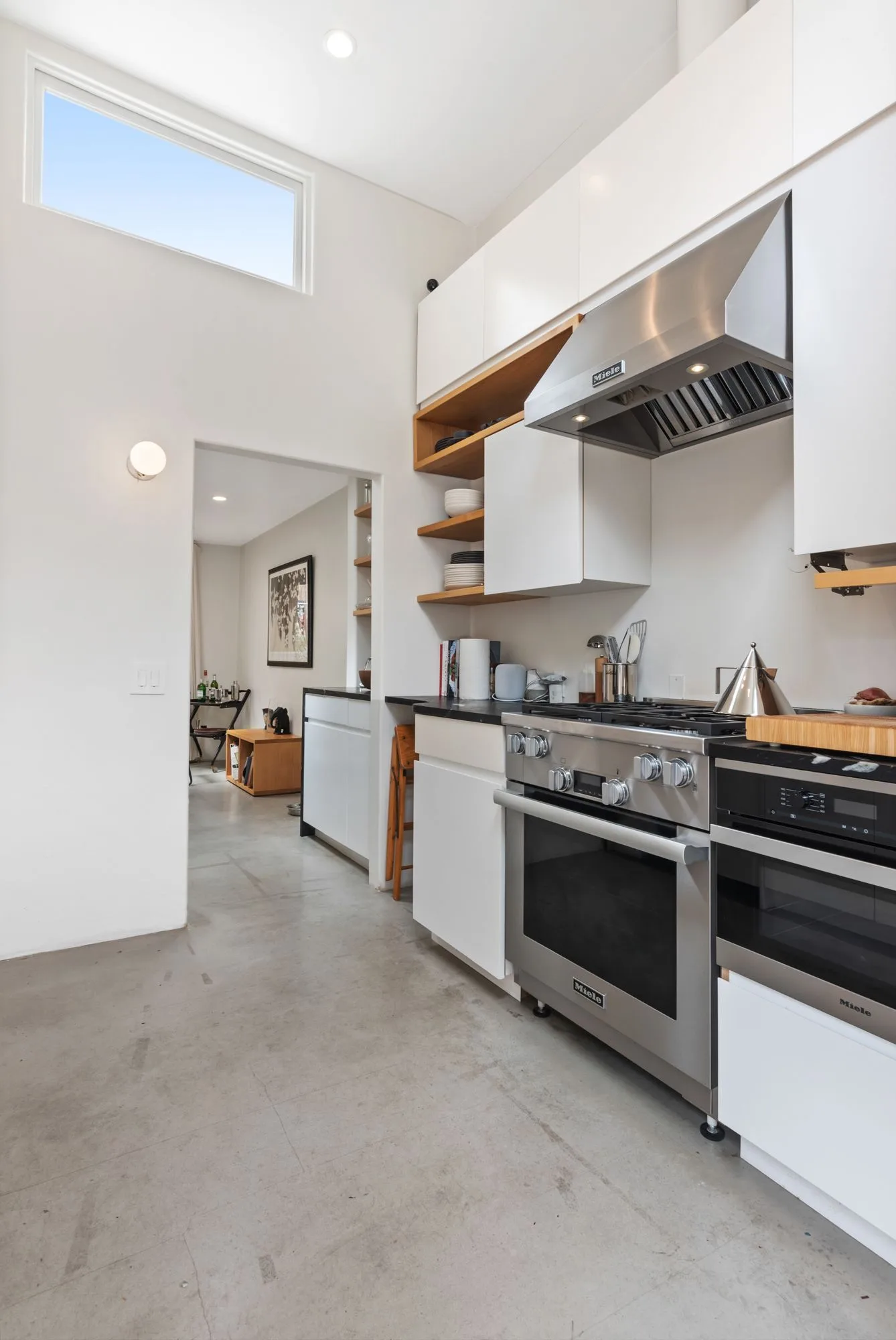 Narrow white kitchen with timber shelves, a range hood and a clerestory window — furniture and millwork designed and built by Jack Rusk (Oakland and Los Angeles, 2013–2018)