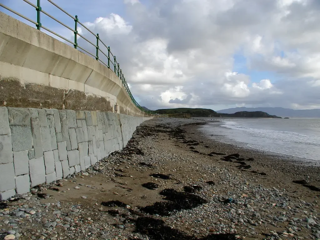 View of a beach with stone and sand shoreline, illustrating coastal soft mitigation strategies discussed in research on natural infrastructure for disaster risk reduction